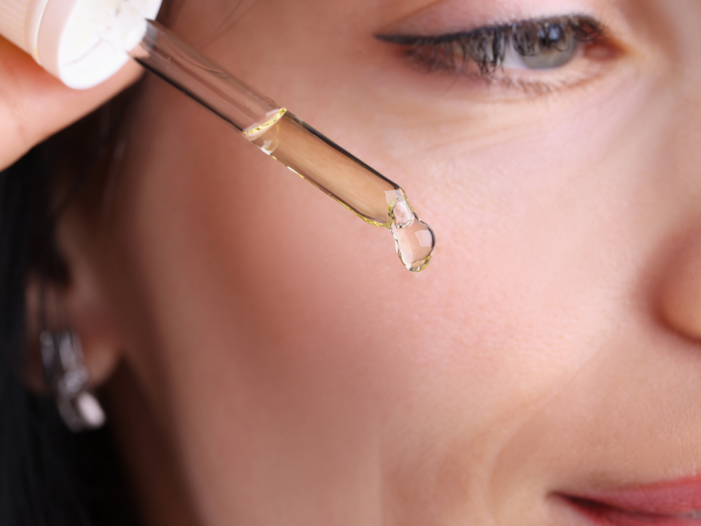 A picture of a woman releasing a drop of oil cleanser from the dropper. 