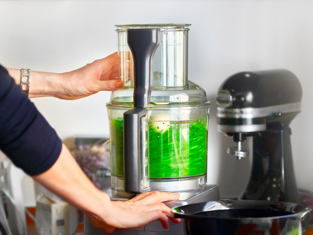 A woman operating a food processor in the kitchen.