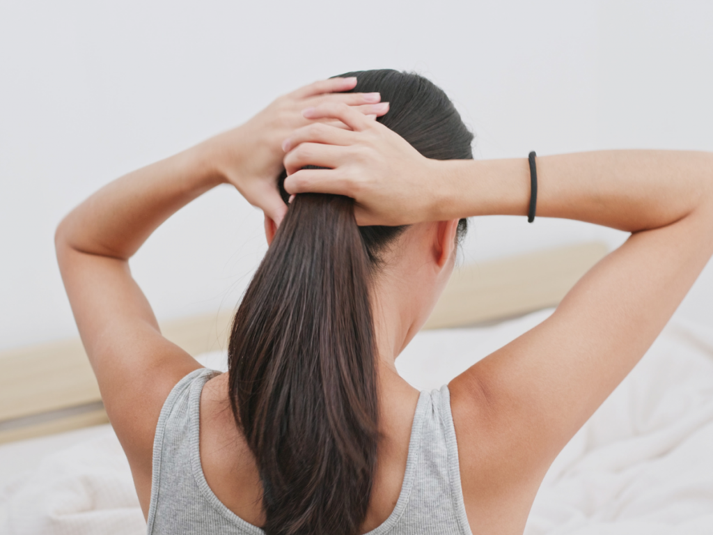 Haircare Essentials: A picture of a woman using a hair tie to keep her hair together.
