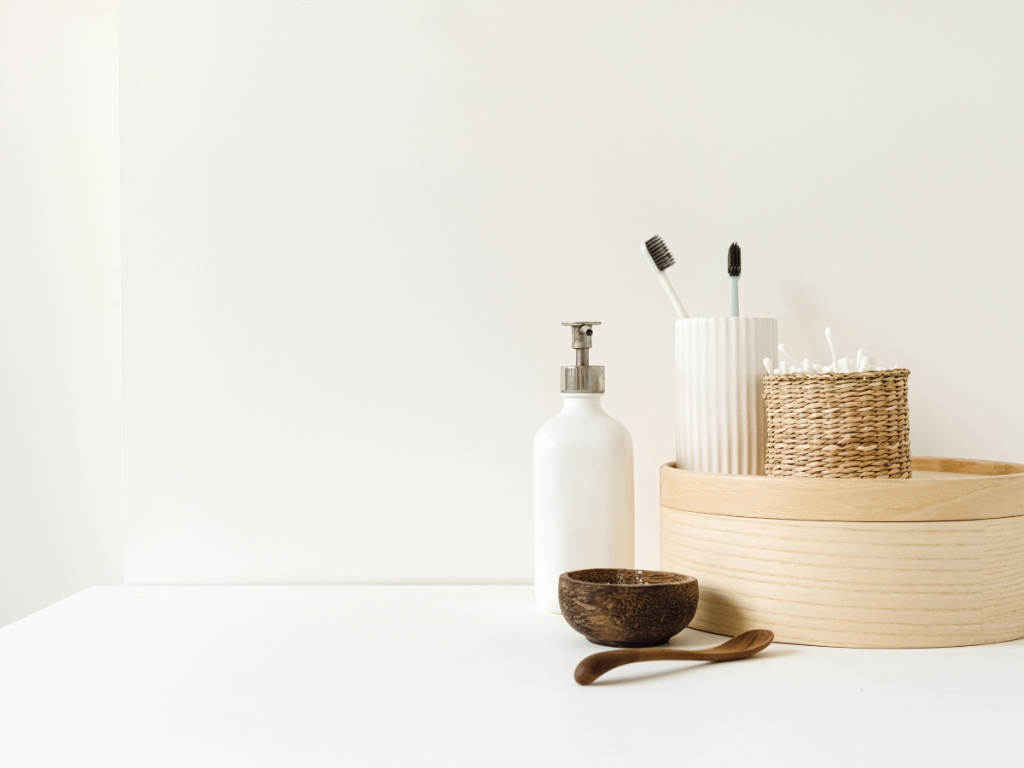A picture of a simplified organized countertop with a dispenser, wooden bowl and various containers