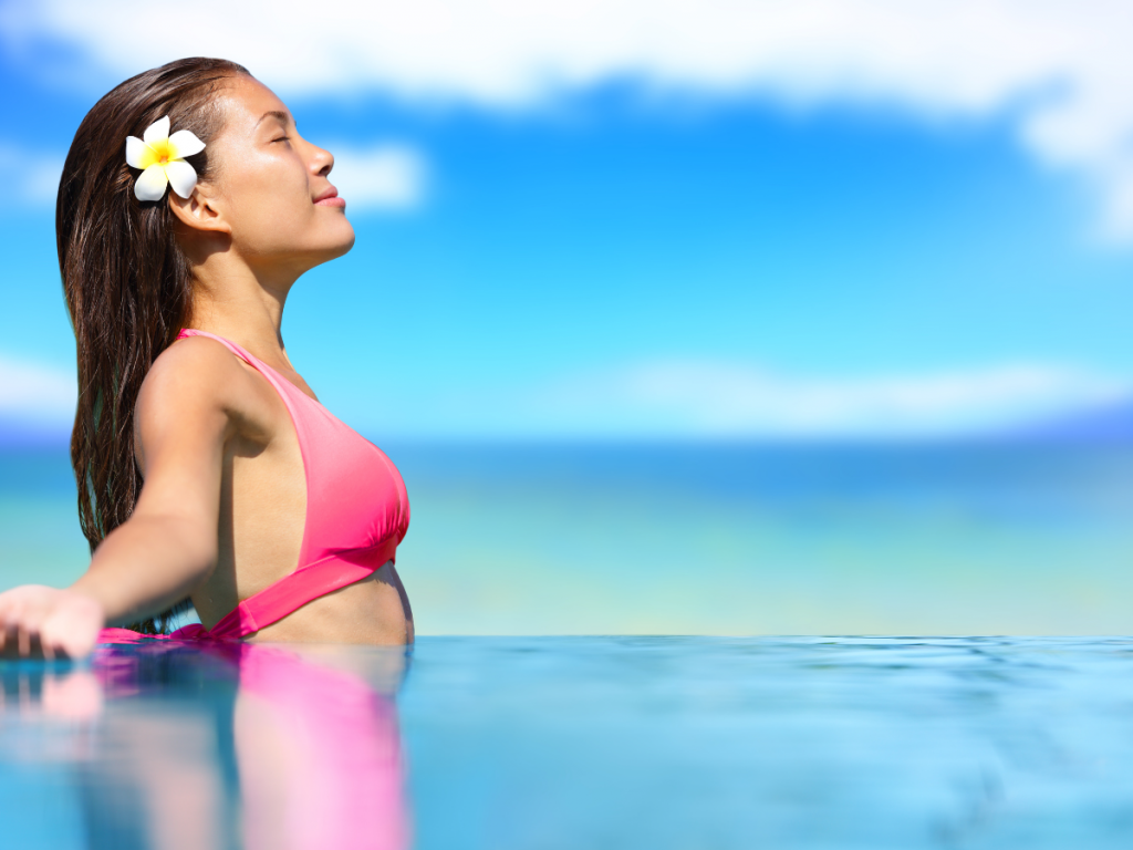 A picture of a woman in an infinity pool with her head tilted back and her eyes closed.